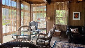 A cozy room with wicker furniture, a glass table, and a leather couch. - American House 1854- Steamboat Landing, 4 Bedrooms, 1.5 Bath, Full Kitchen (McGregor)