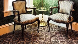 A room with two upholstered chairs, a table with a lamp, a large window, and a framed picture on the wall. - American House 1854- Steamboat Landing, 4 Bedrooms, 1.5 Bath, Full Kitchen (McGregor)
