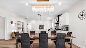 A modern kitchen with white cabinets, a wooden dining table, and black chairs.