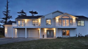 A two-story house with a garage, a balcony, and a driveway. - Perch - La Fiesta 34: Luxe Retreat w/ Serenity View & Firelit Comfort (Coupeville)