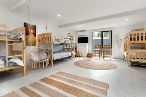A children's room with bunk beds, a hanging chair, a television, and a large window.
