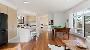 Een moderne keuken met een centraal eiland, houten vloeren en een pooltafel.