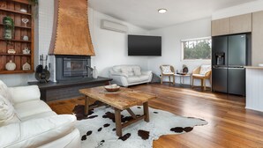 Een moderne woonkamer met een open haard, een flatscreen televisie, een bank en een eettafel.