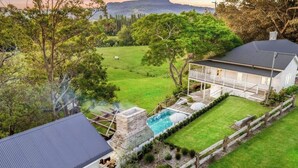 A house with a stone pool, a fenced yard, and a view of the surrounding landscape. - 'Torrente House' - Berry, NSW (Berry)