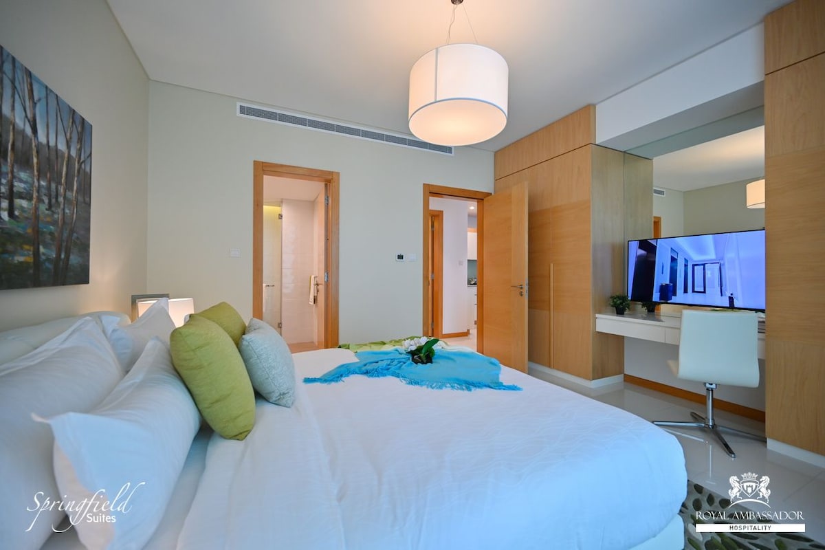 A modern hotel room with a large bed, a television, and a desk area.