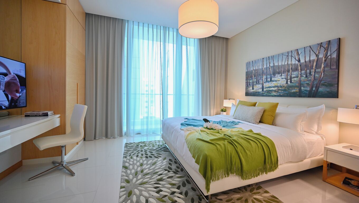 Una habitació d'hotel moderna amb un llit gran, una taula de treball amb una cadira, una televisió i un quadre a la paret.