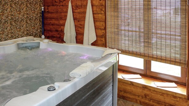 A hot tub in a room with wooden walls and a window with blinds. - Nice home in Korenica with sauna (Korenica)