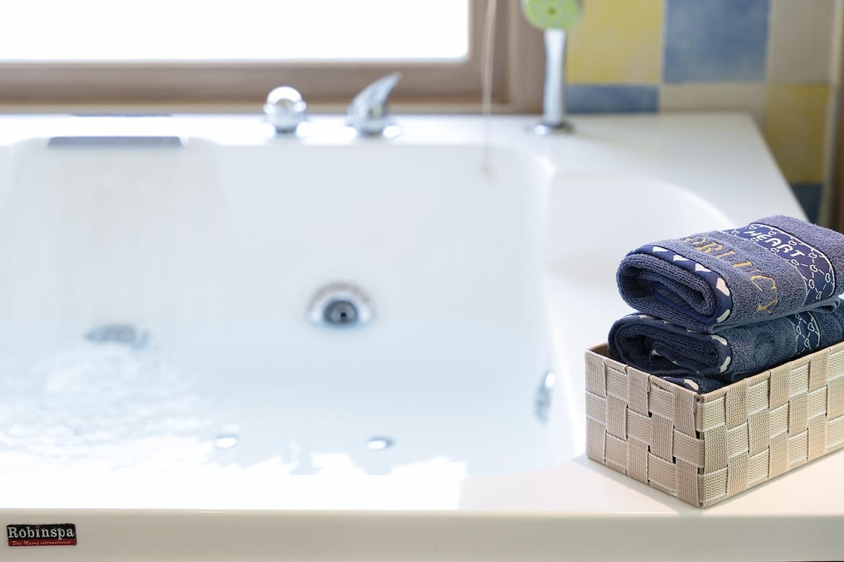 A bathtub with a woven basket containing folded towels.