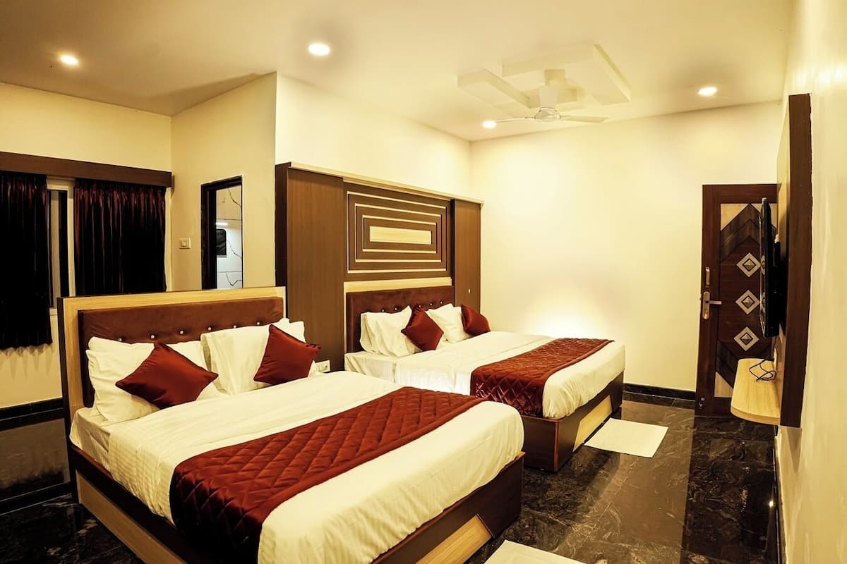 A hotel room with two beds, a wooden headboard, a ceiling fan, and a door with a decorative pattern.