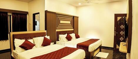 A hotel room with two beds, a wooden headboard, a ceiling fan, and a door with a decorative pattern.
