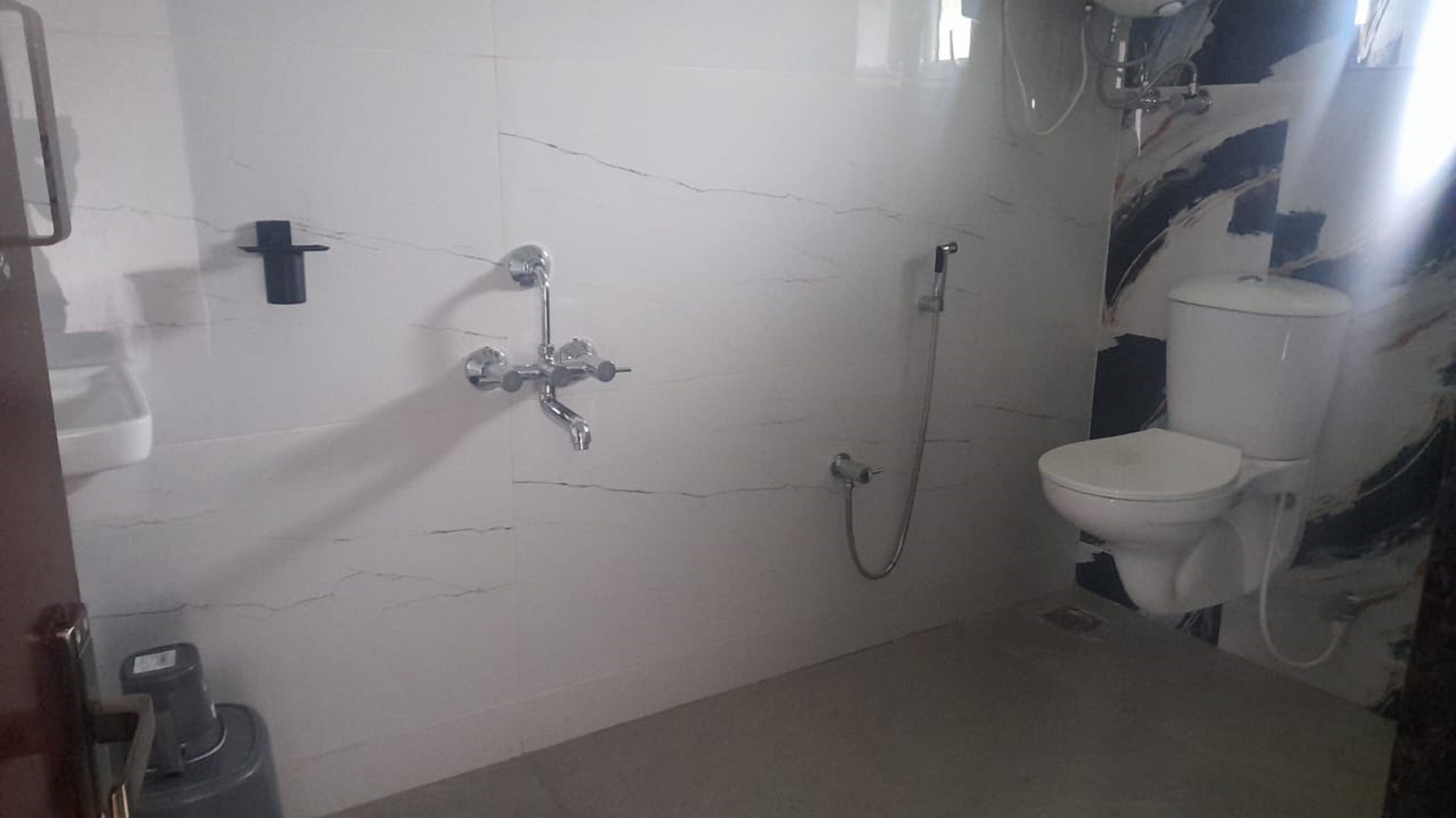 A bathroom with a white tiled wall, a shower, a toilet, and a sink.