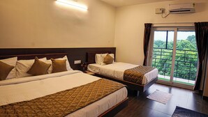 Quarto de hotel com duas camas, ventoinha no teto, ar condicionado e vista para o verde pela janela.