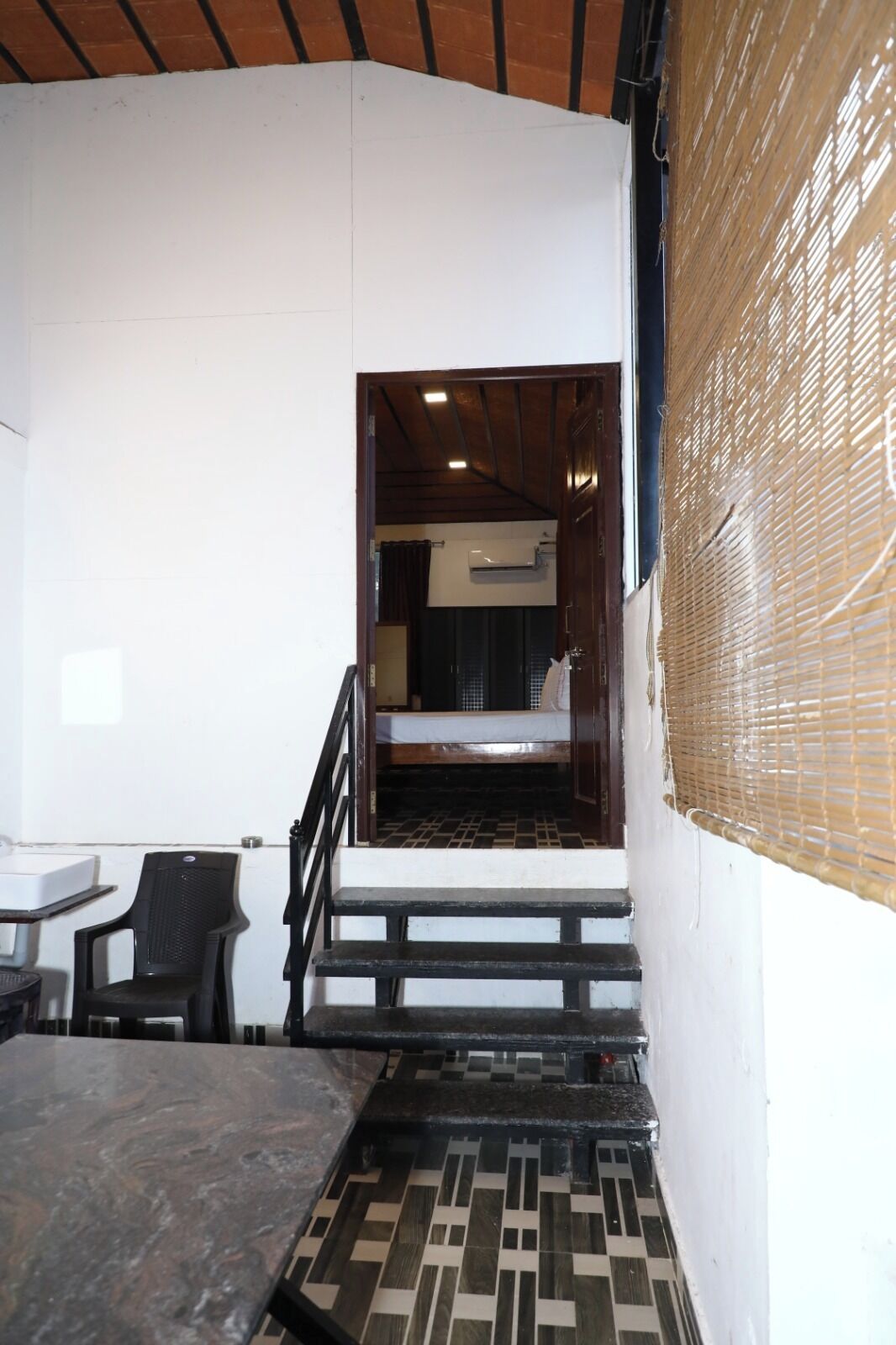 A staircase leading to a bedroom with a bed, a chair, and a small table.