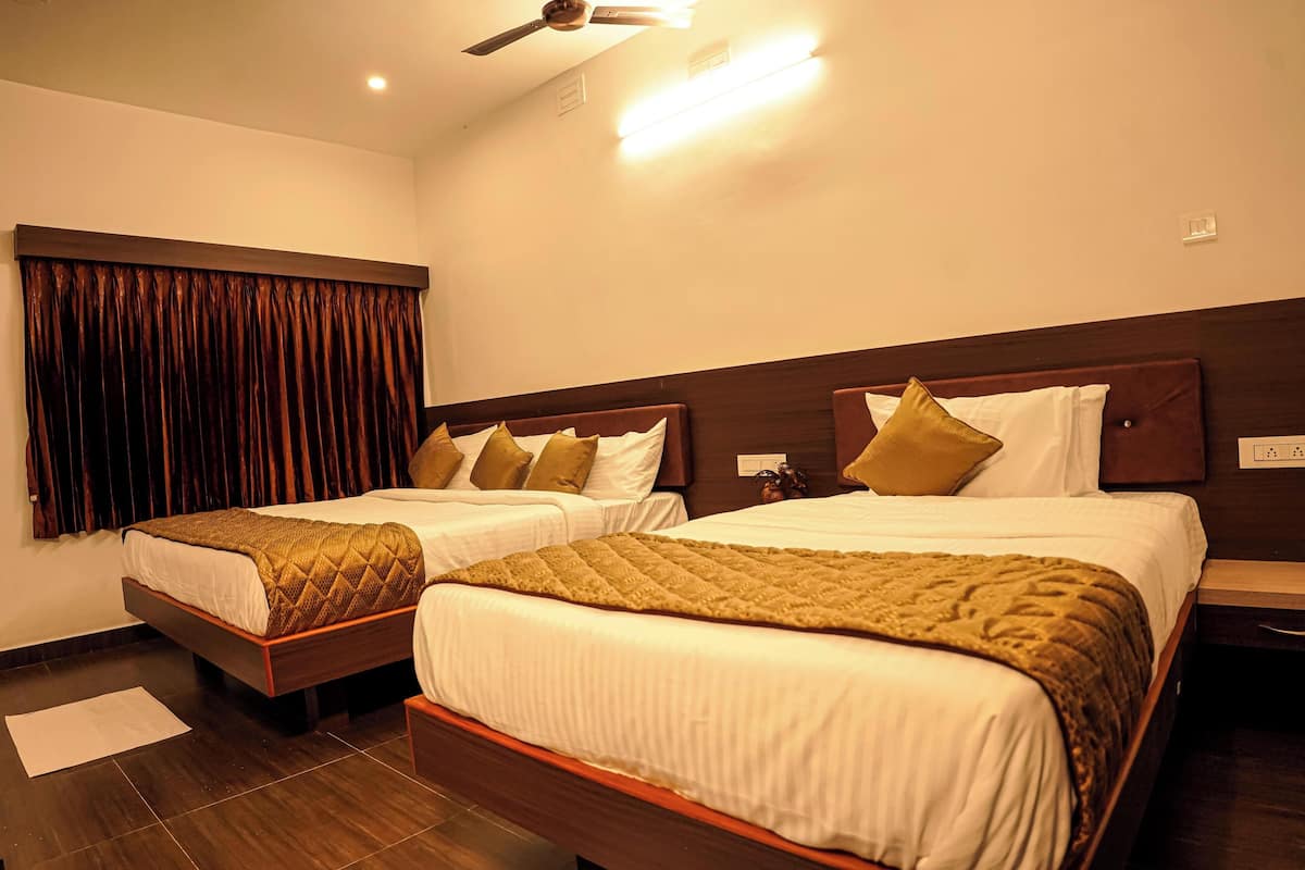 A hotel room with two beds, dark wooden headboards, white bedding, and a brown quilted blanket.