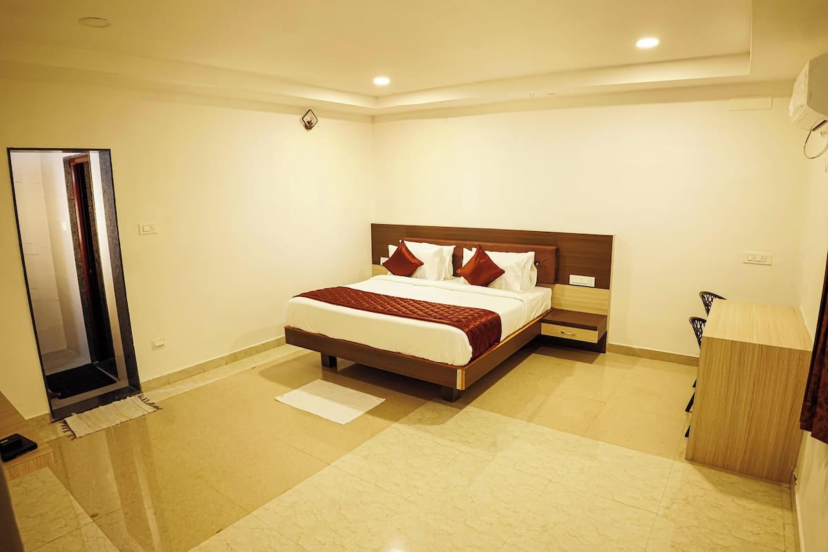 A hotel room with a large bed, a wooden headboard, a nightstand, and a wooden desk.