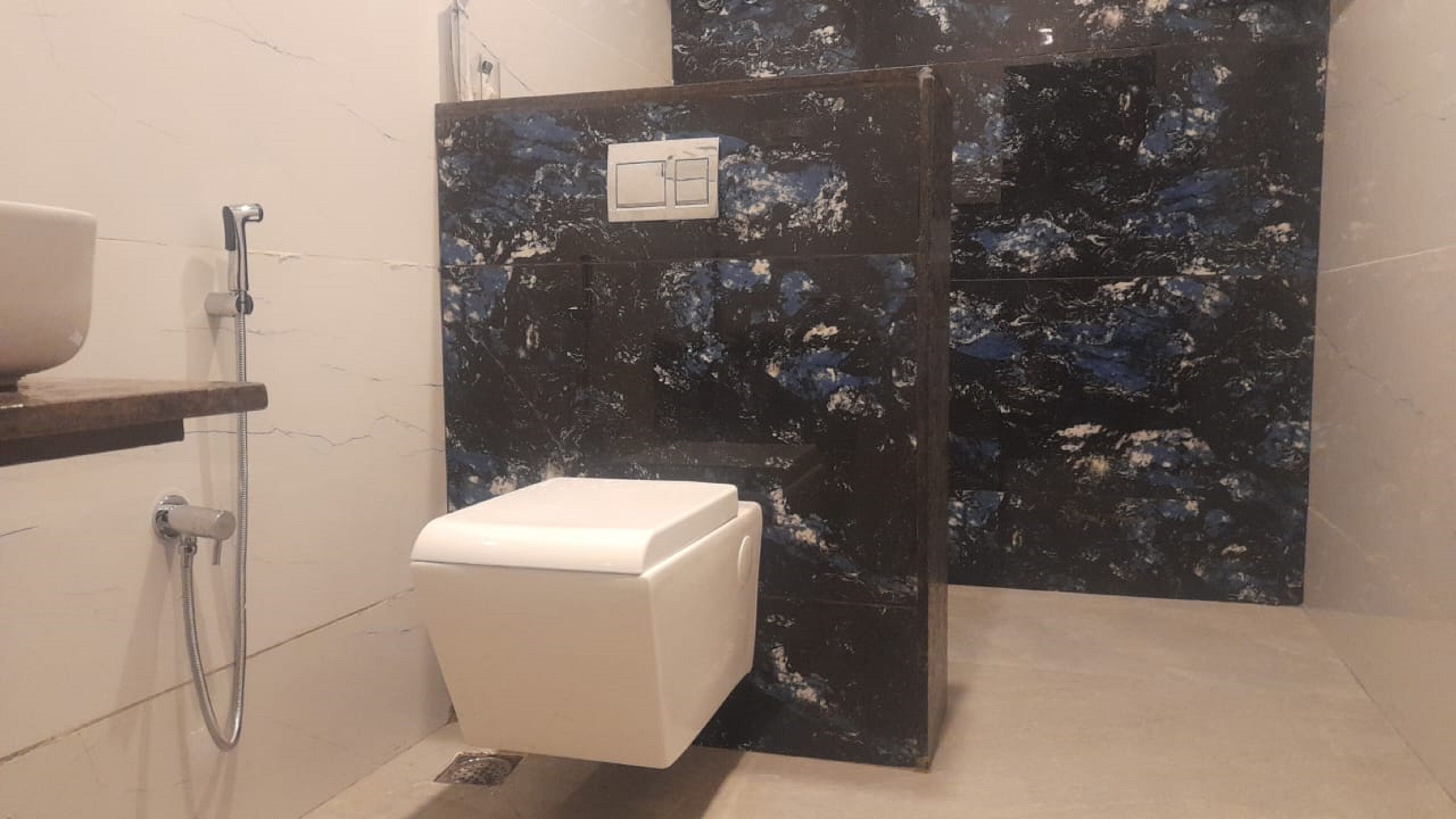 A bathroom with a white toilet, a shower area, and a marble backsplash.