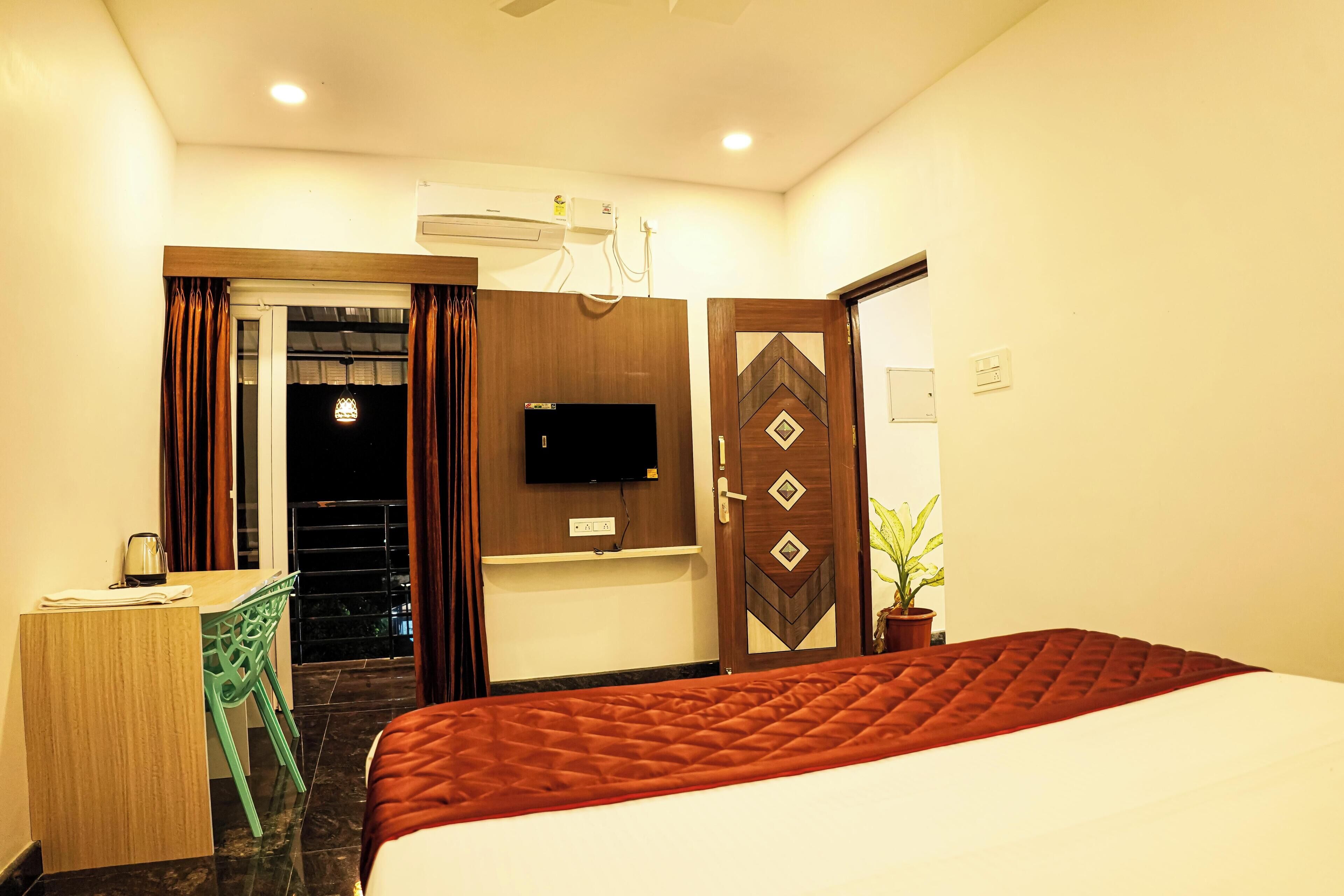 A hotel room with a bed, a desk, a television, and a door with a decorative pattern.