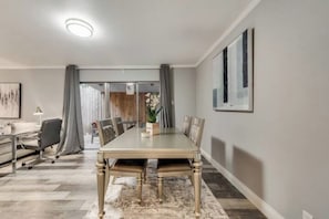 A modern dining area with a long table, chairs, and a rug.