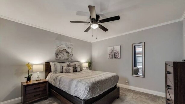 A bedroom with a bed, nightstand, ceiling fan, and artwork on the walls.