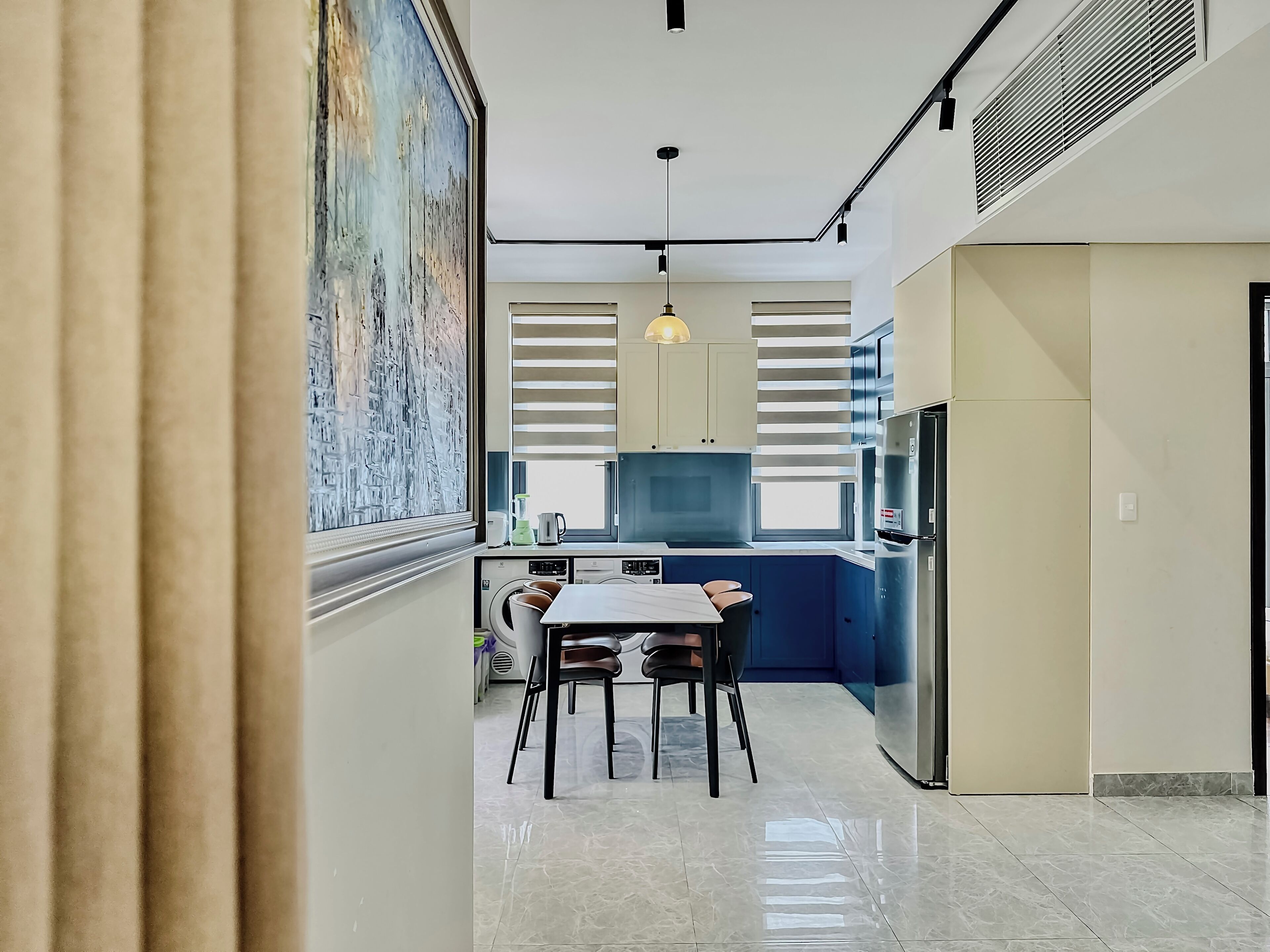 Una cocina moderna con comedor, un amplio ventanal y un cuadro en la pared.