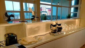 A kitchen with a marble countertop, a coffee maker, a rice cooker, and a coffee machine. - Sukun Hotel (Cilacap)