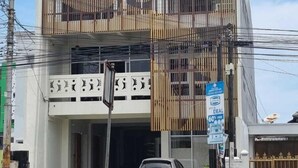 A two-story building with a balcony on the upper floor, a car parked in front, and a sign advertising a sale. - Sukun Hotel (Cilacap)