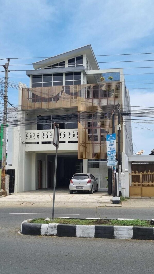 A two-story building with a balcony on the upper floor, a car parked in front, and a sign advertising a sale. - Sukun Hotel (Cilacap)