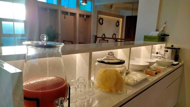 A kitchen counter with a fruit punch dispenser, a glass jar with a lid, and various food items. - Sukun Hotel (Cilacap)