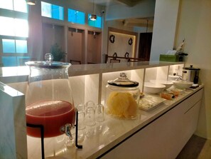 A kitchen counter with a fruit punch dispenser, a glass jar with a lid, and various food items. - Sukun Hotel (Cilacap)