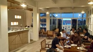 A dining area with a long table, chairs, and a kitchen counter visible in the background. - Sukun Hotel (Cilacap)