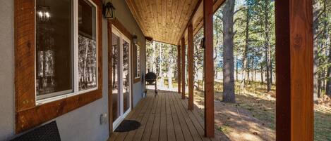 Une terrasse en bois couverte, offrant une vue sur une forêt.