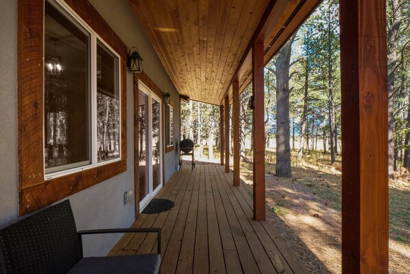 Una terraza cubierta de madera con vistas a un bosque.