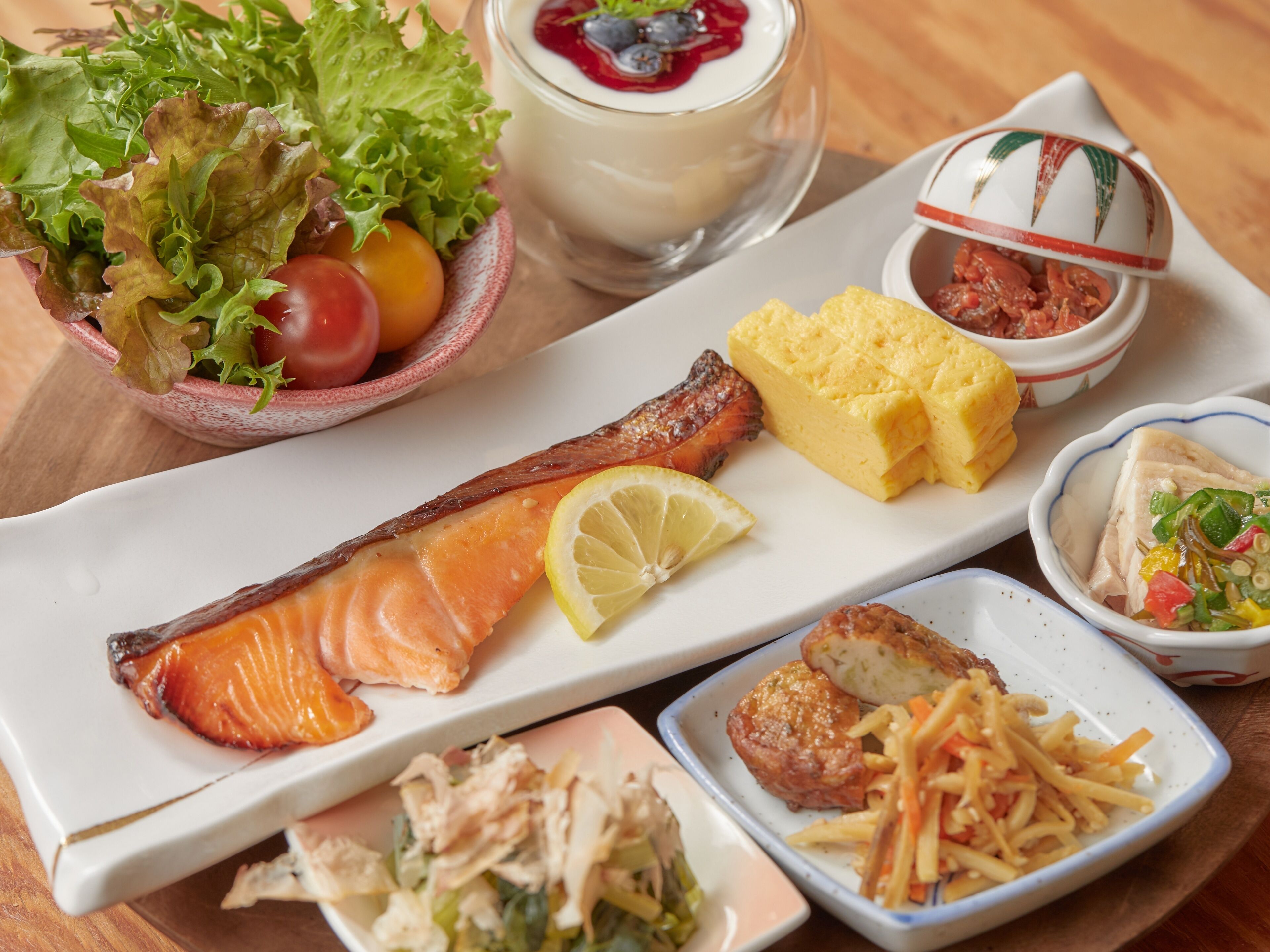 Variedad de platos que incluyen salmón, huevos y verduras sobre una mesa.