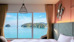 Habitación de hotel con una cama grande, vistas al mar y un adorno decorativo en la pared.