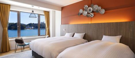 A modern hotel room with two large beds, a view of the water, and a decorative wall piece.