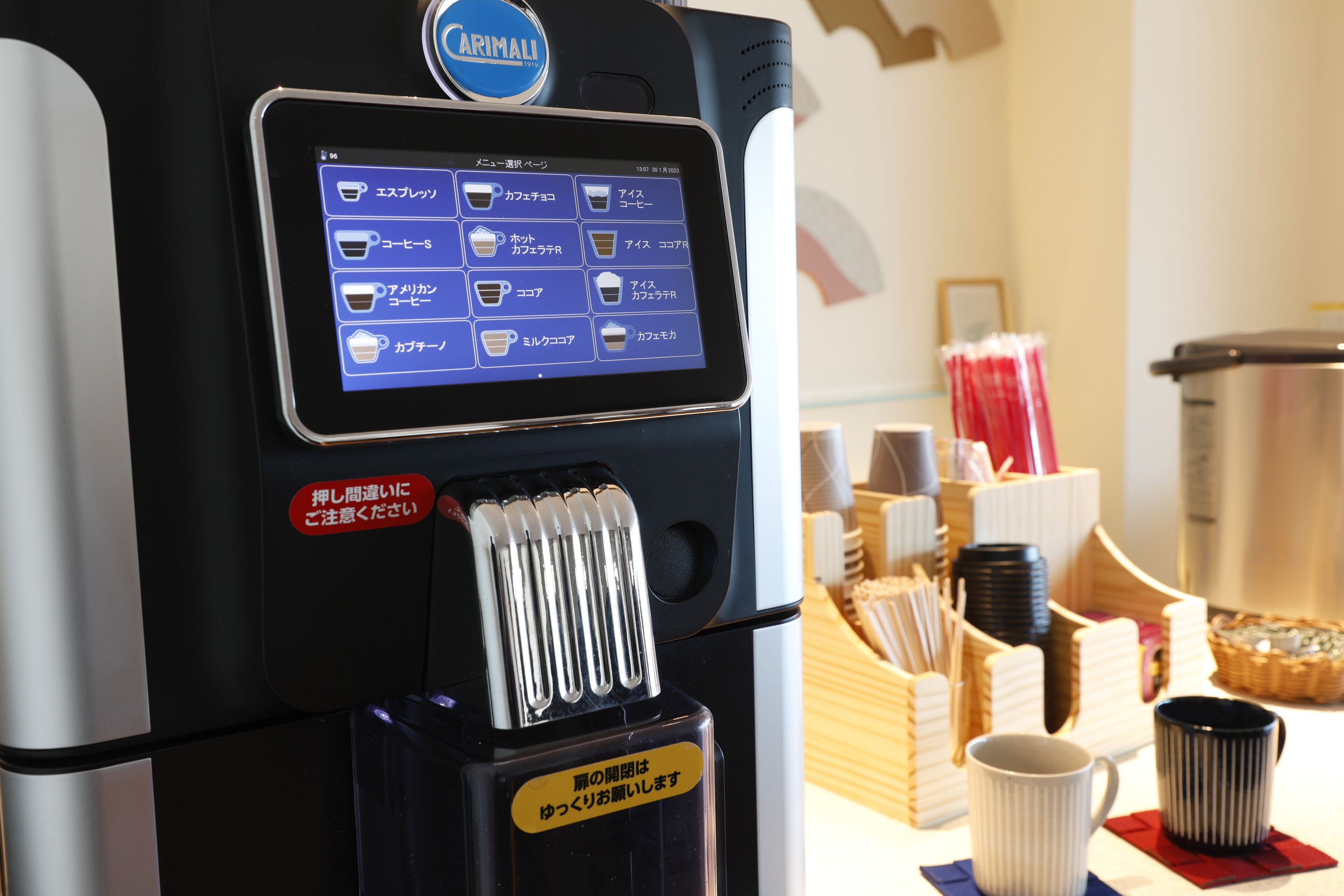 A coffee machine with a digital display menu and a coffee cup holder.