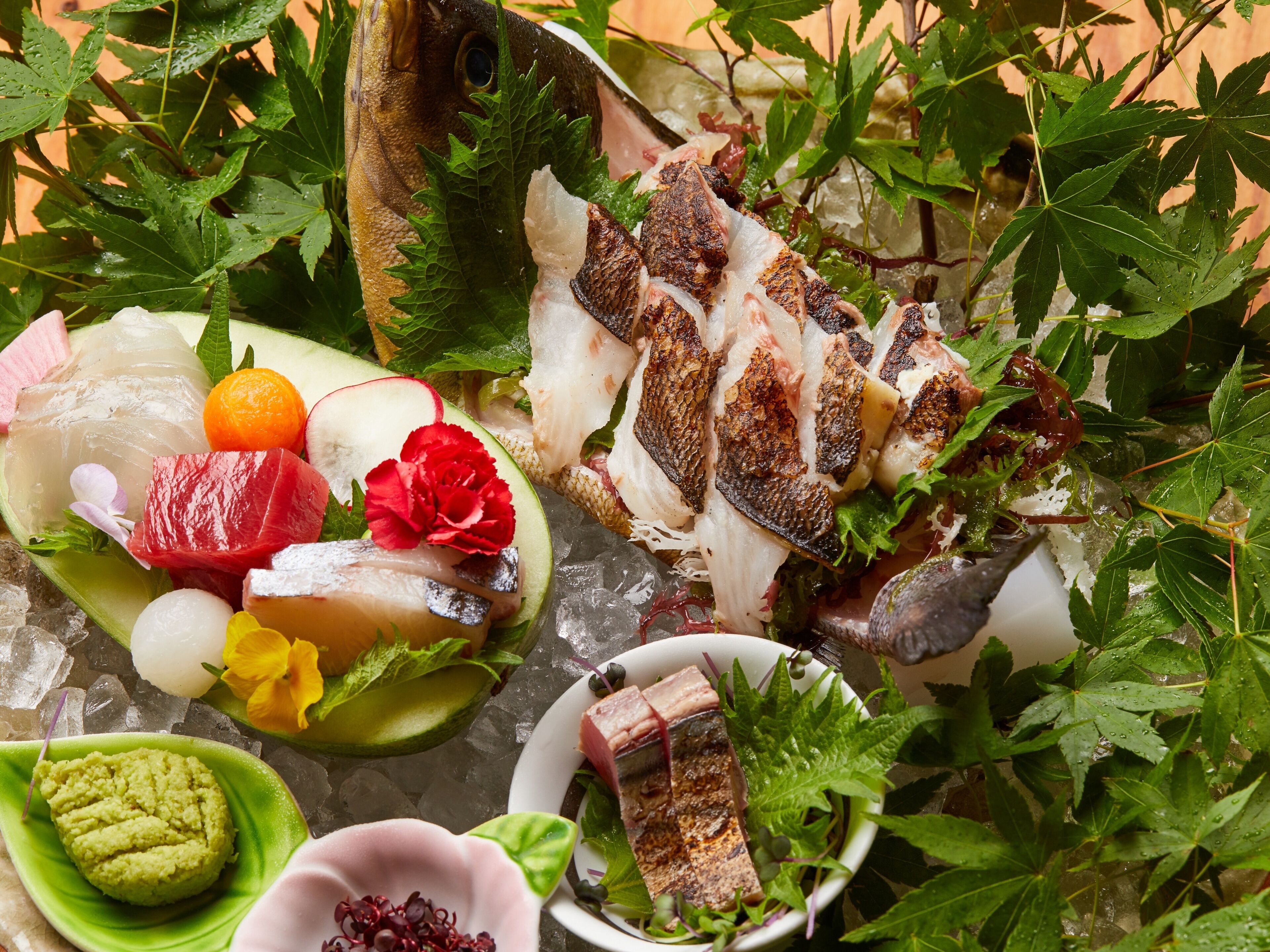 A variety of seafood and vegetables on a plate, surrounded by ice and greenery.