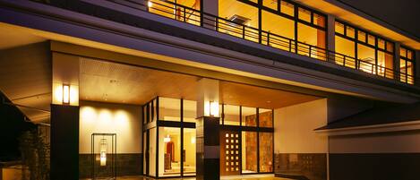 A modern hotel with a spacious entrance, a covered outdoor area, and a second-floor balcony with large windows.