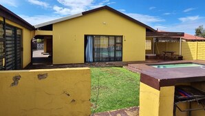 Un bâtiment jaune doté d’une piscine, d’un patio couvert et d’une cour clôturée.