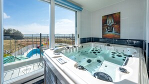 A modern bathroom with a large bathtub, a view of a water park, and a painting on the wall. - Ganghwa Hanabi Pension (Incheon)