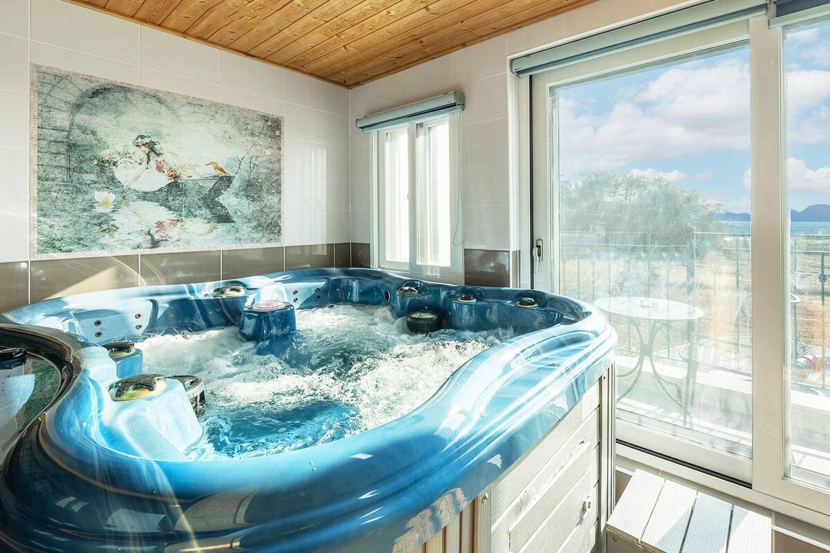 A hot tub on a balcony with a view of a playground and mountains.