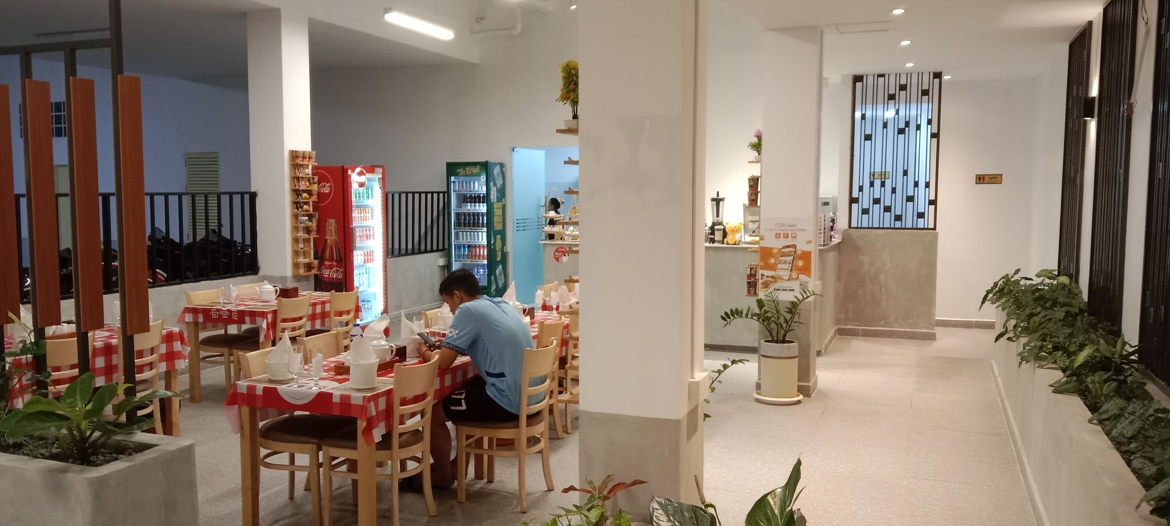A restaurant with checkered tablecloths, wooden chairs, and a person using a mobile device.