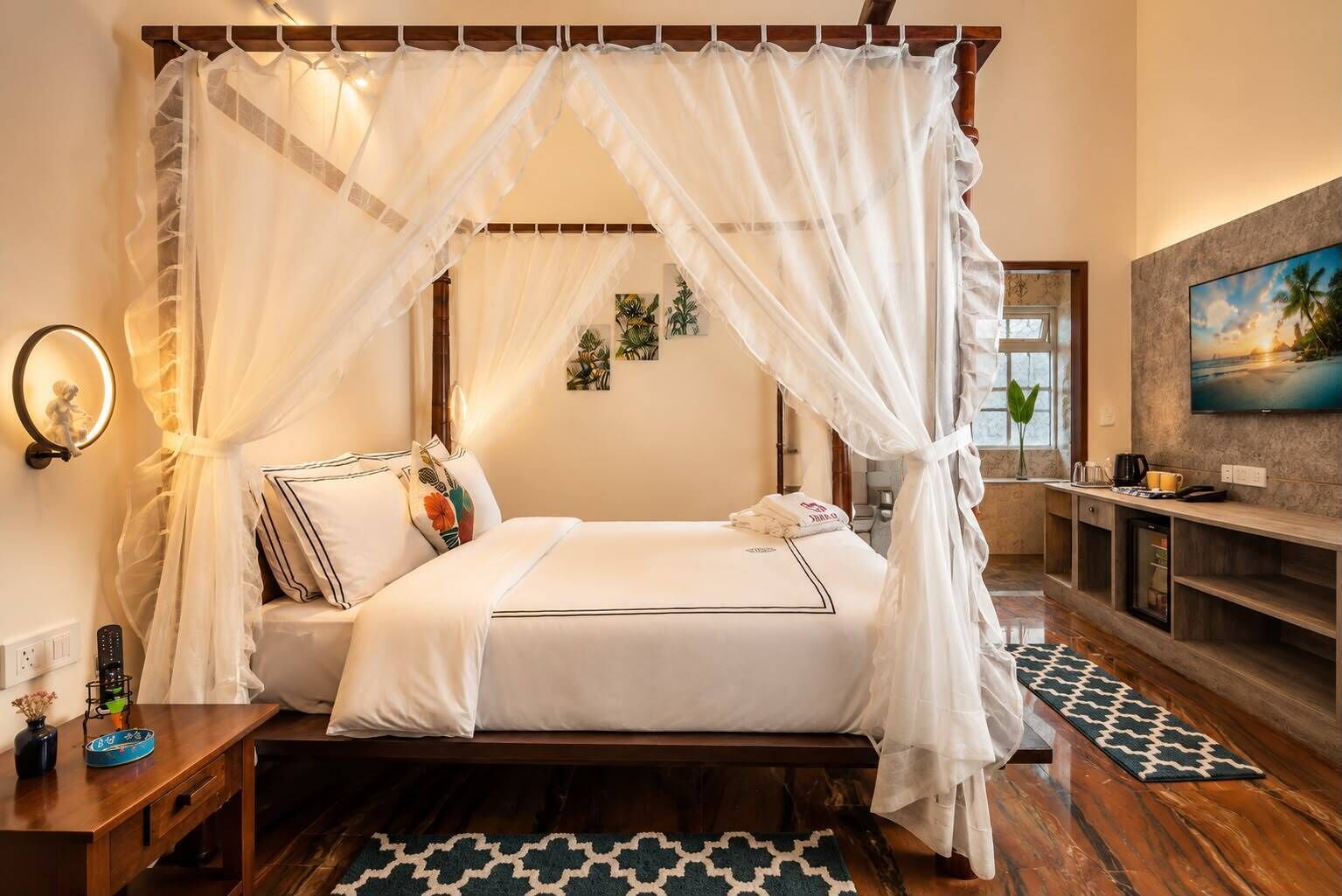 Quarto com cama de dossel, mesa de cabeceira com abajur, televisão de tela plana na parede e piso de madeira.
