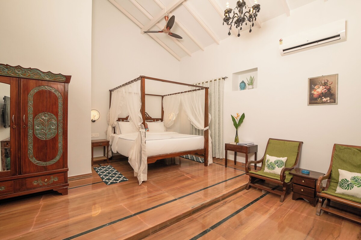 A bedroom with a four-poster bed, wooden furniture, and a chandelier.