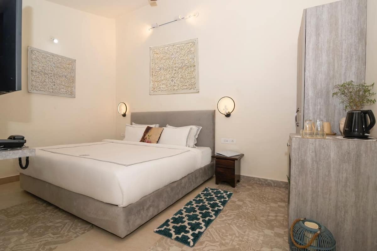 A neatly arranged hotel room with a large bed, bedside tables, decorative wall art, and a small desk with a telephone.