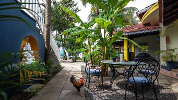 Un patio con una mesa, sillas, una estatua y un gallo.