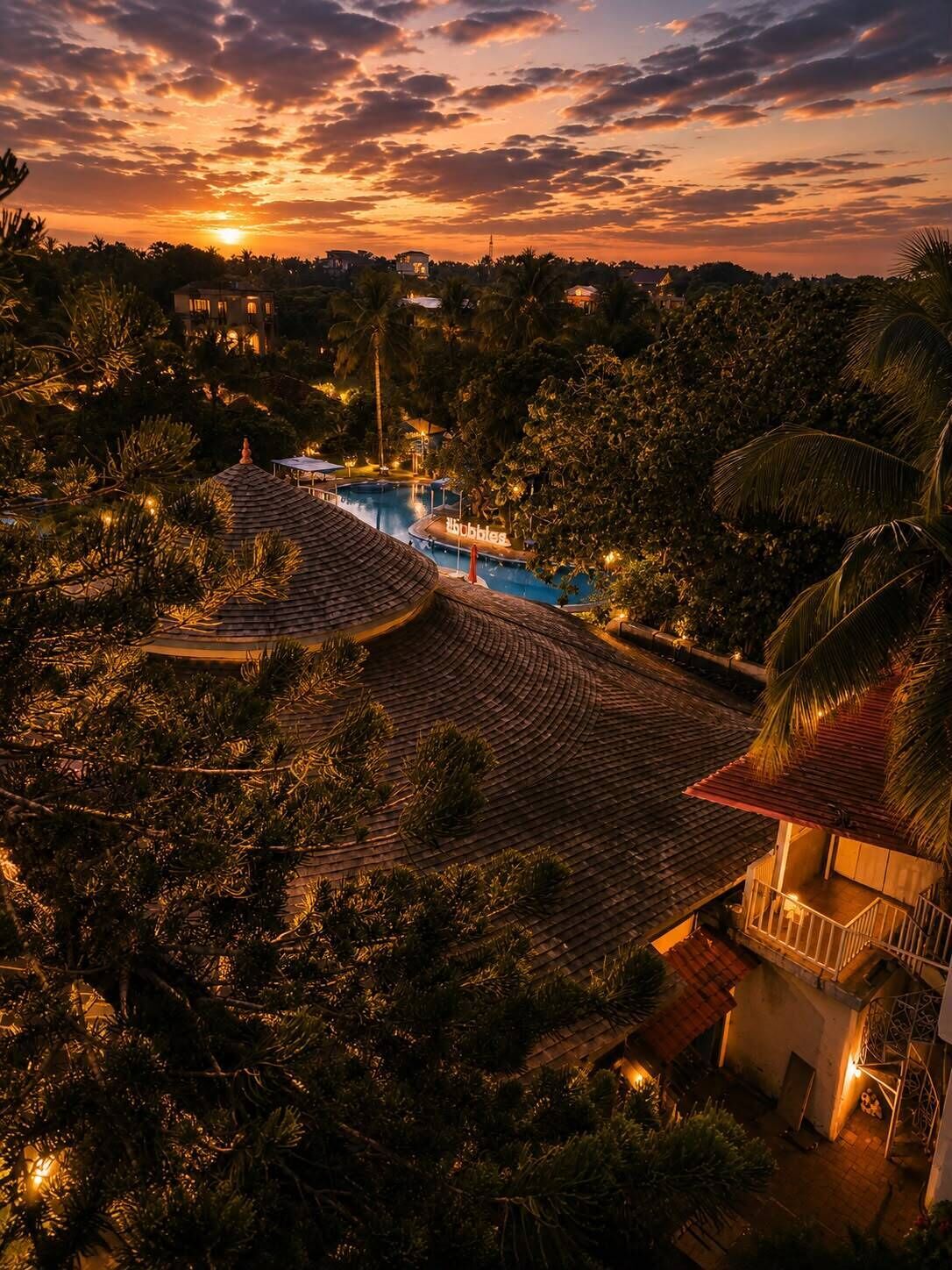 A resort with a swimming pool, palm trees, and a sunset view.