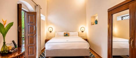 A bedroom with a bed, bedside lamps, a mirror, and a wooden door.