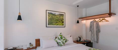A neatly arranged hotel room with a bed, bedside table, and a wall-mounted coat rack.