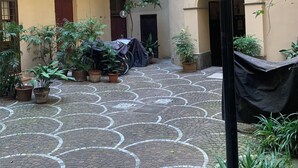 A courtyard with potted plants, a covered motorcycle, and a tiled floor with circular patterns.